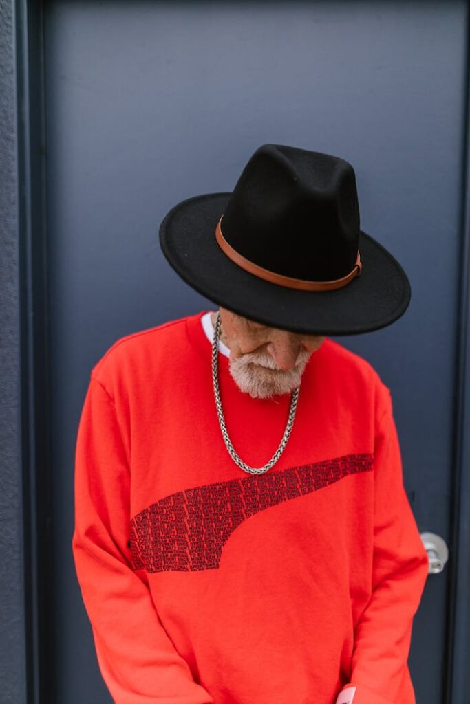 Stylish Elderly Man wearing Red Sweater and Black Fedora Hat 
